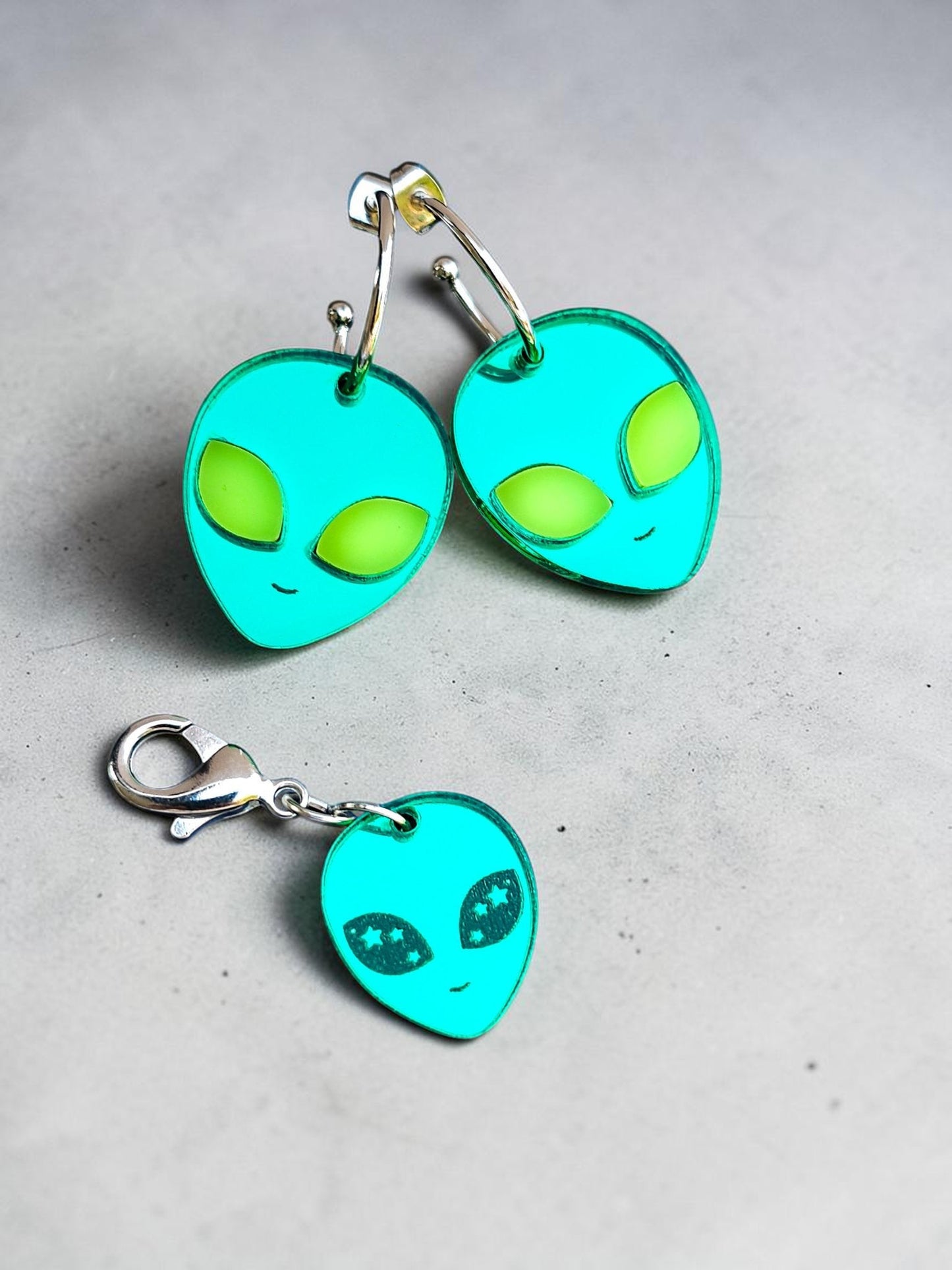 Morti's Fun Club alien face earrings in cosmic mirror acrylic with lime fluorescent eyes and silver-plated hoops.