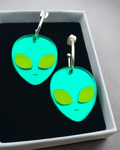 Morti's Fun Club alien face hoop earrings in mirrored teal acrylic with fluorescent lime green eyes in a gift box.