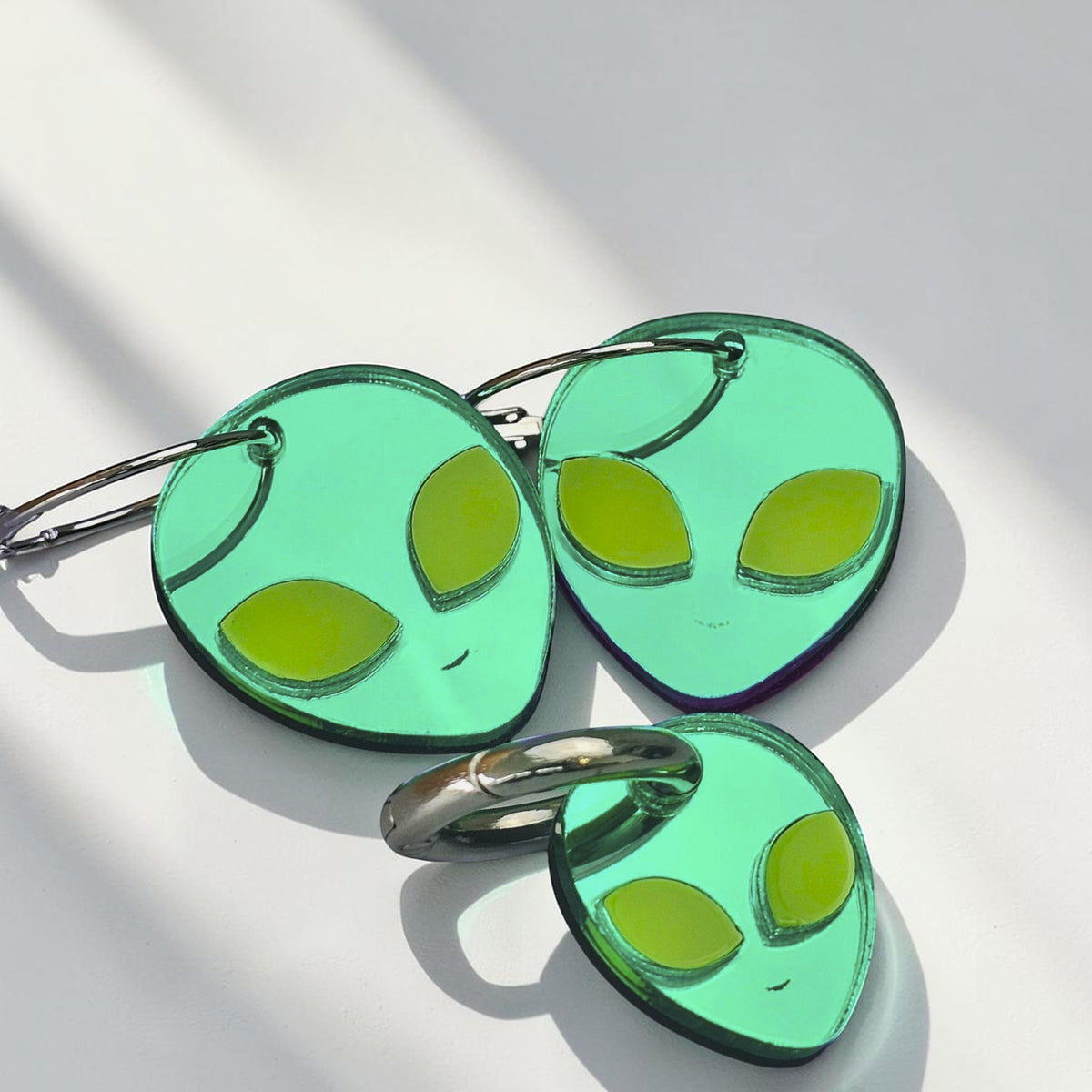 Morti's Fun Club green acrylic alien hoop earrings and matching dog collar charm set on a light blue background