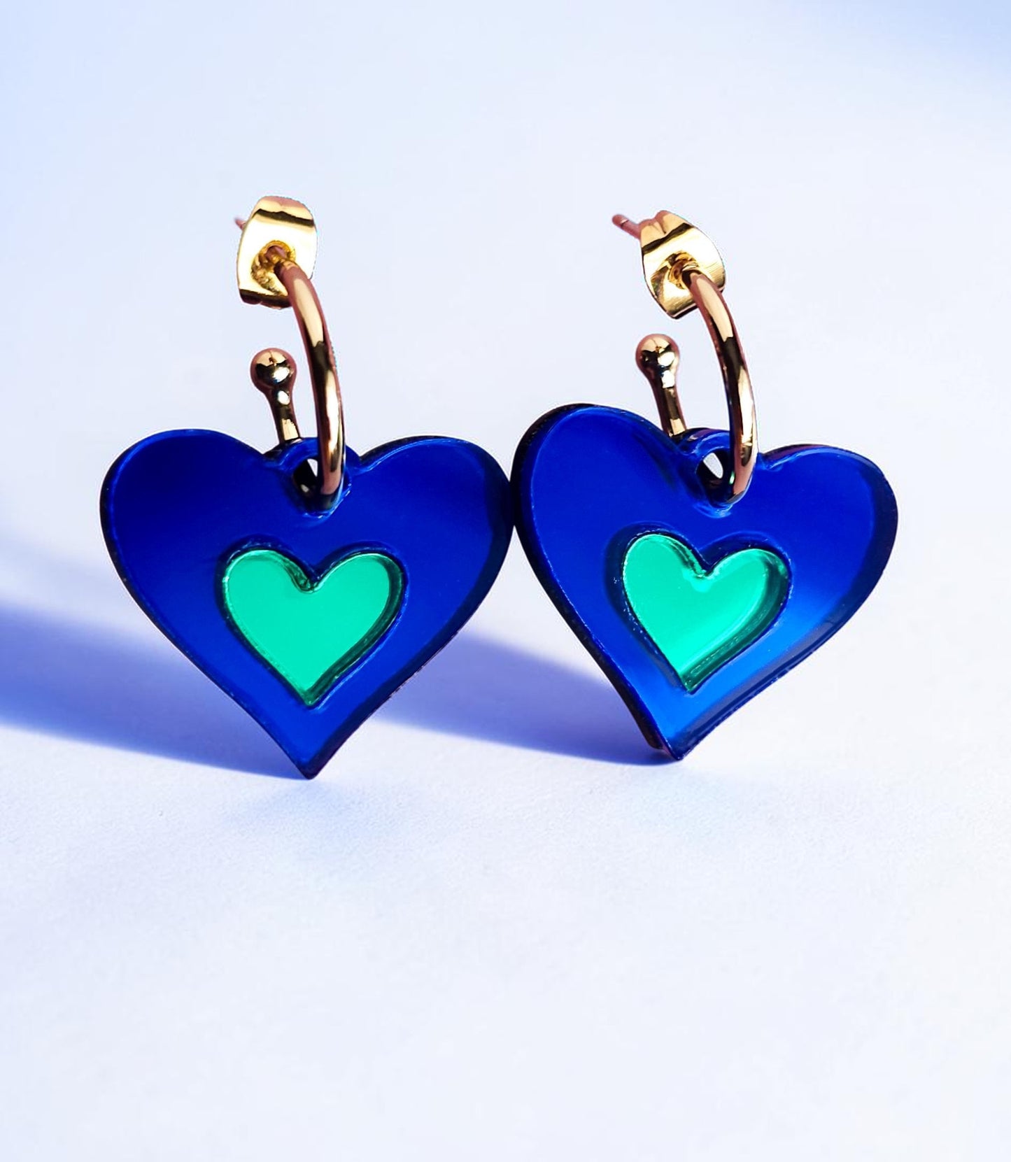 Morti's Fun Club I Heart Dogs heart-shaped earrings in royal blue and green mirrored acrylic with gold hoops.