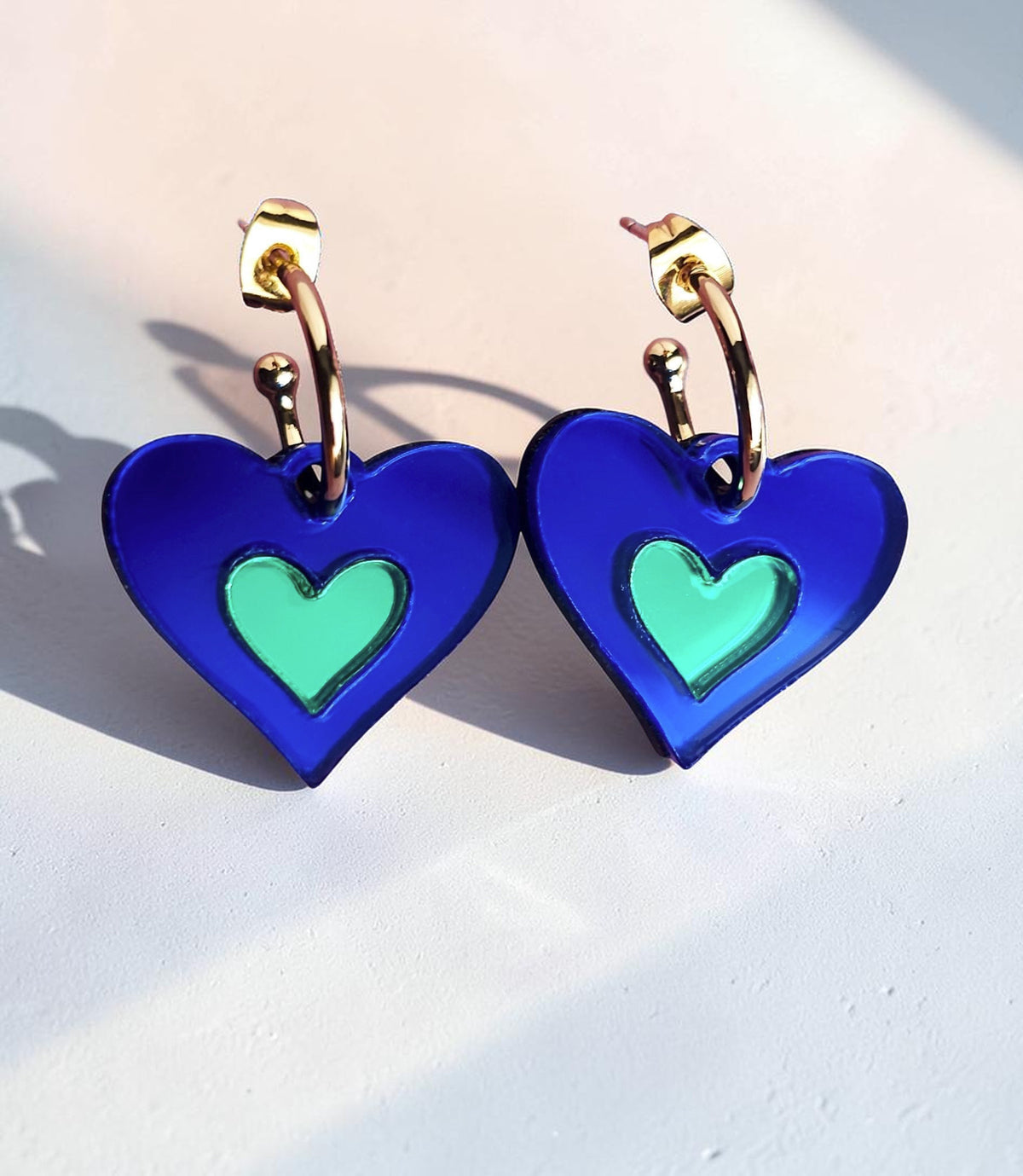 Morti's Fun Club I Heart Dogs heart-shaped earrings in royal blue and green mirrored acrylic with gold hoops.