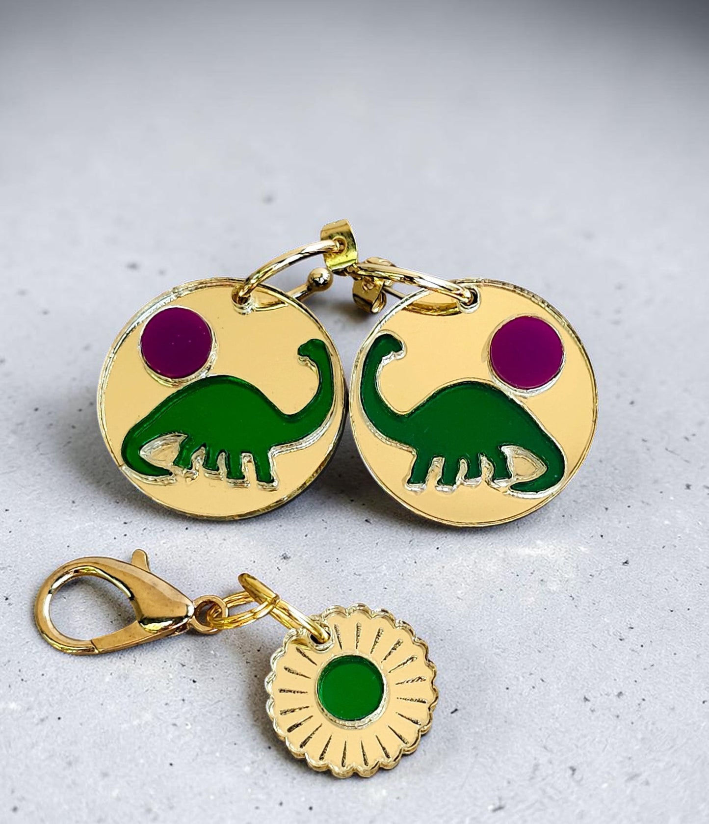 Morti's Fun Club Tiny Dino earrings featuring gold acrylic discs with green dinosaurs and pink moons on gold hoops