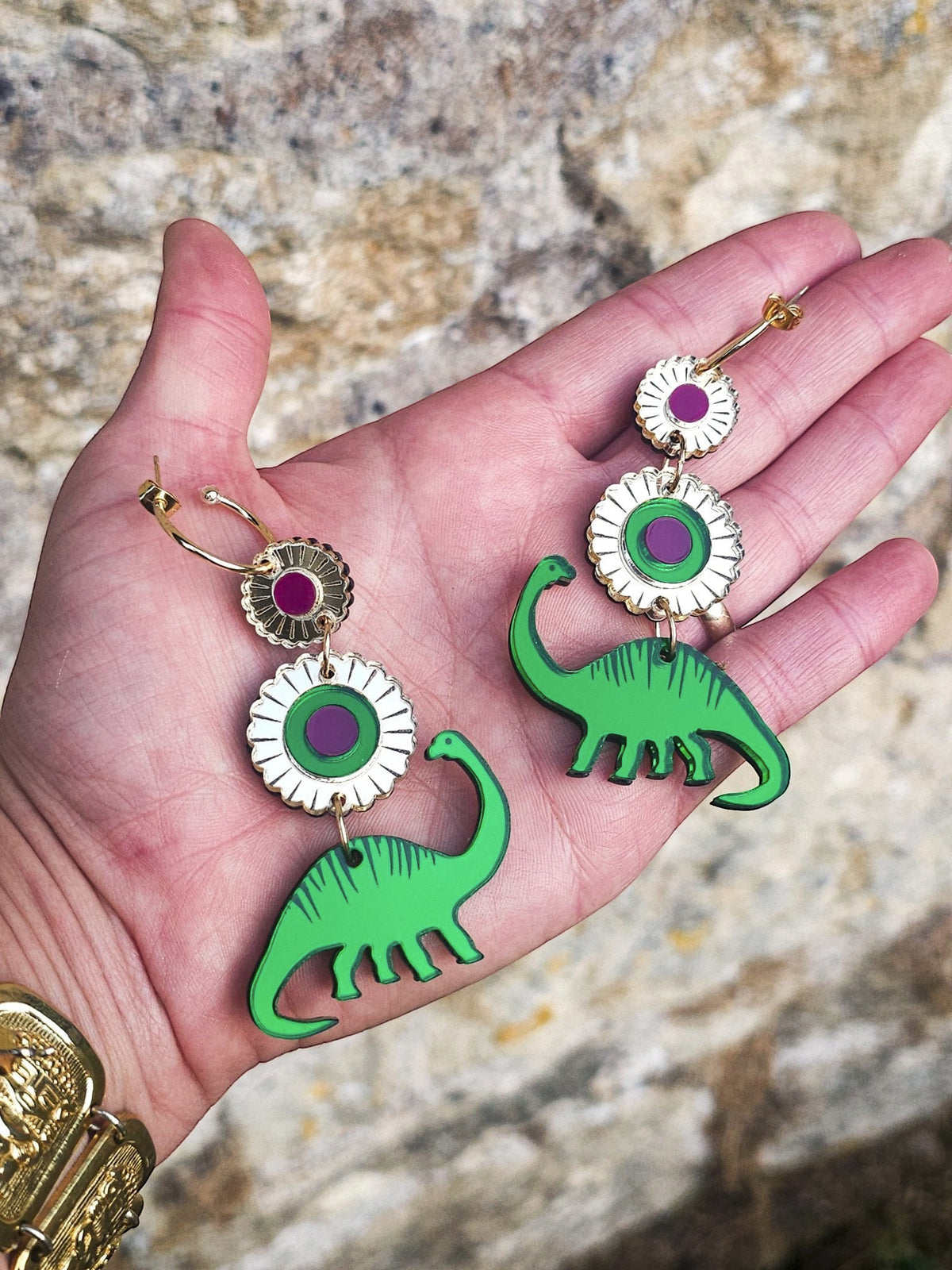 Morti's Fun Club Dino Royalty statement earrings featuring green dinosaur charms and gold-mirrored floral accents.