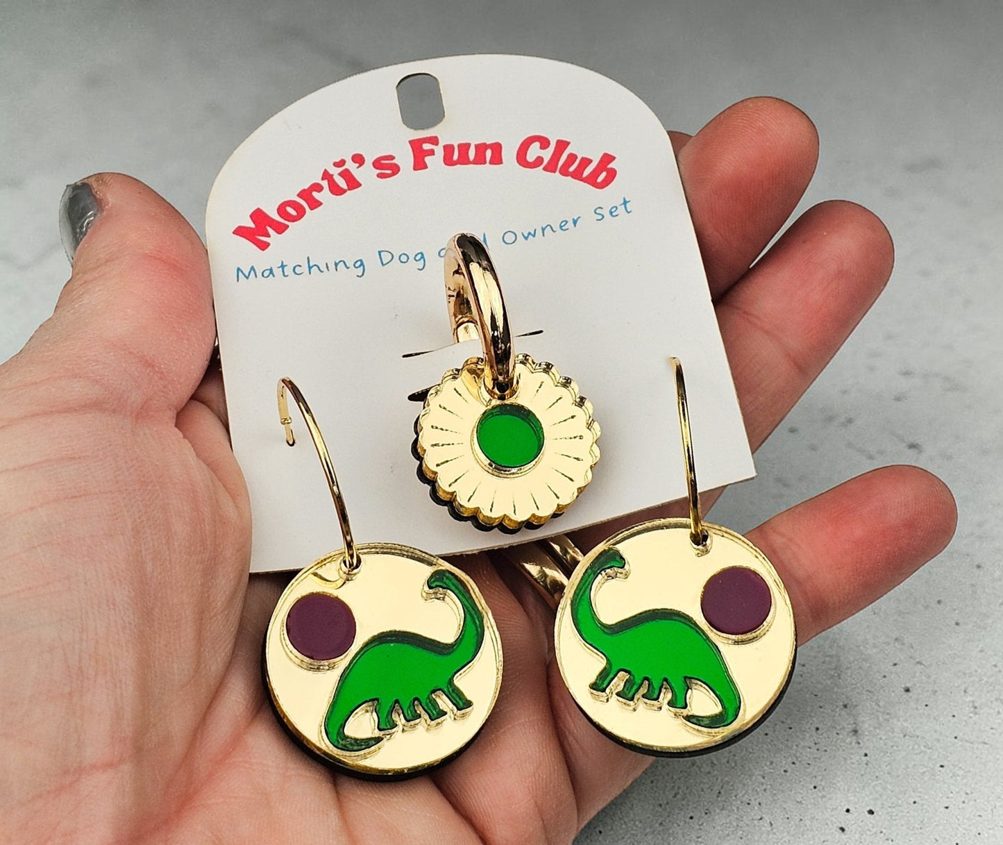 Morti's Fun Club gold-mirrored acrylic earrings and matching dog collar charm featuring green dinosaurs and purple suns