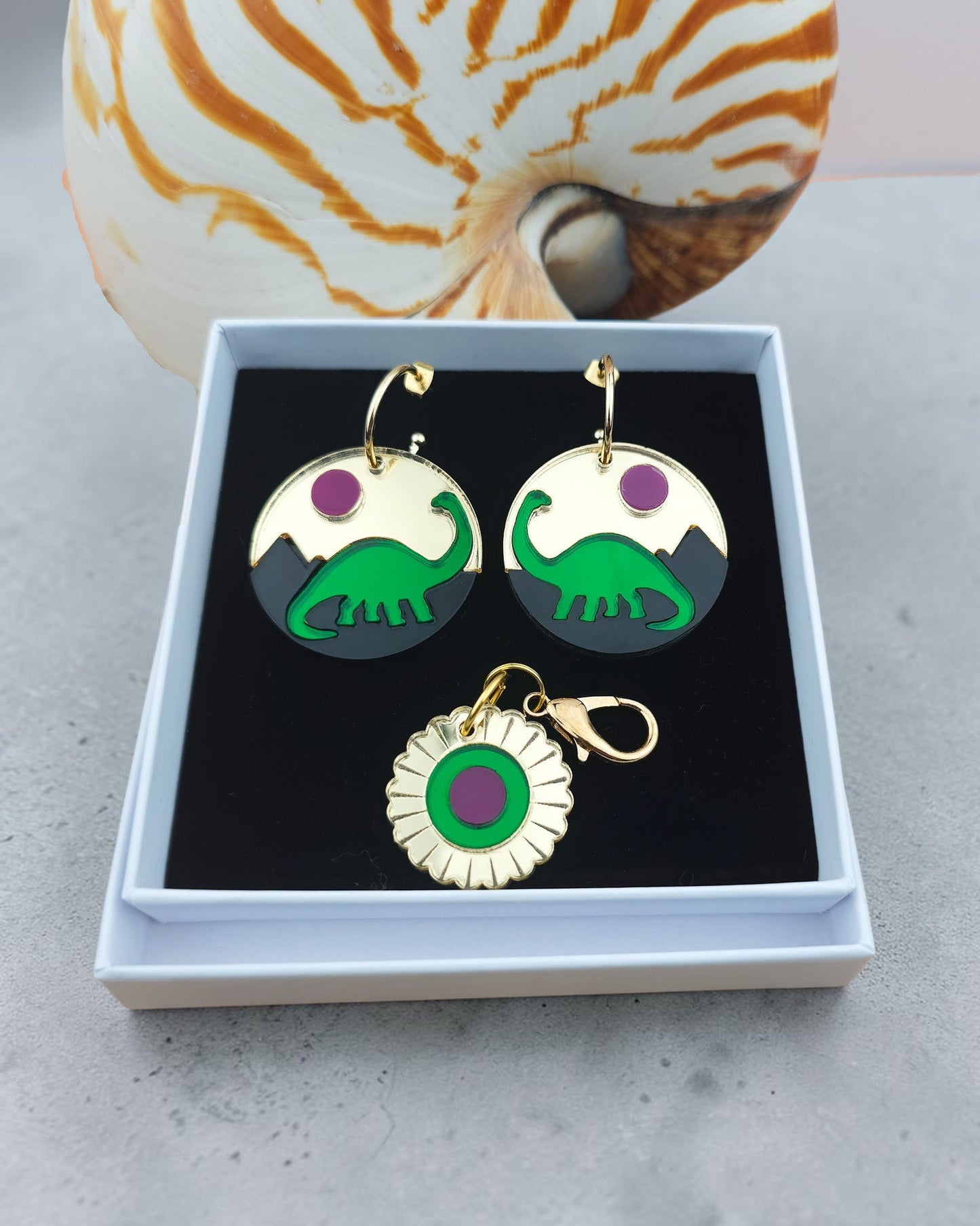 Morti's Fun Club Jurassic Moonrise earrings and matching charm featuring layered green dinosaur and pink sun design.
