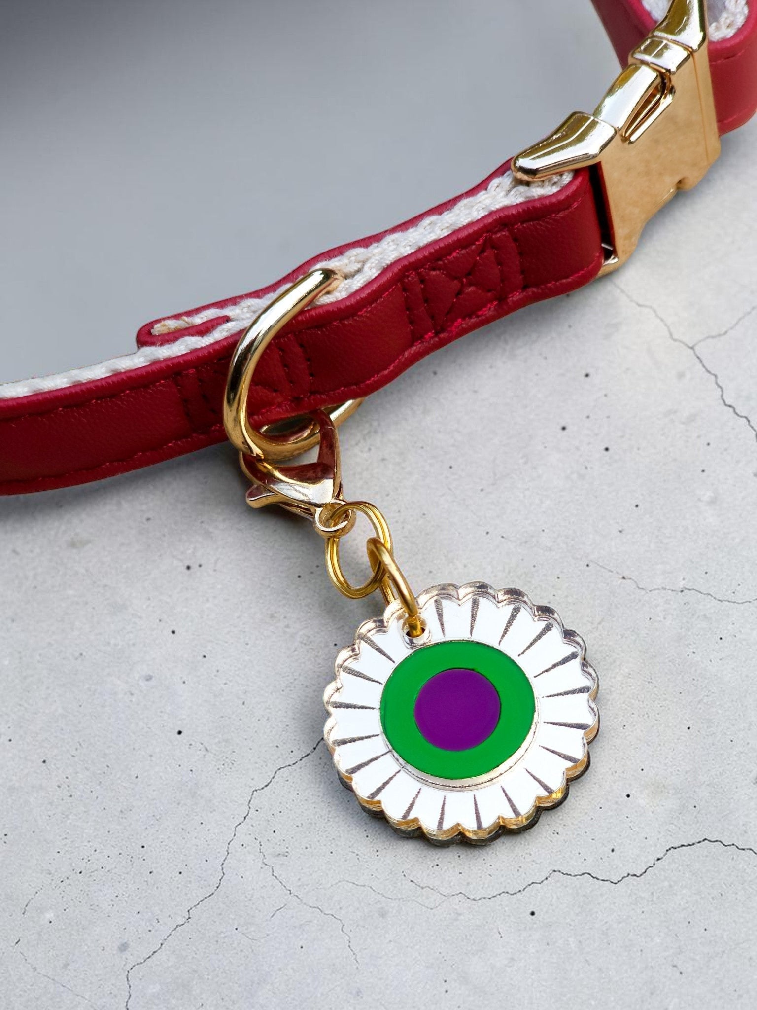 Morti's Fun Club mirror acrylic flower collar charm with green and purple center on a red dog collar