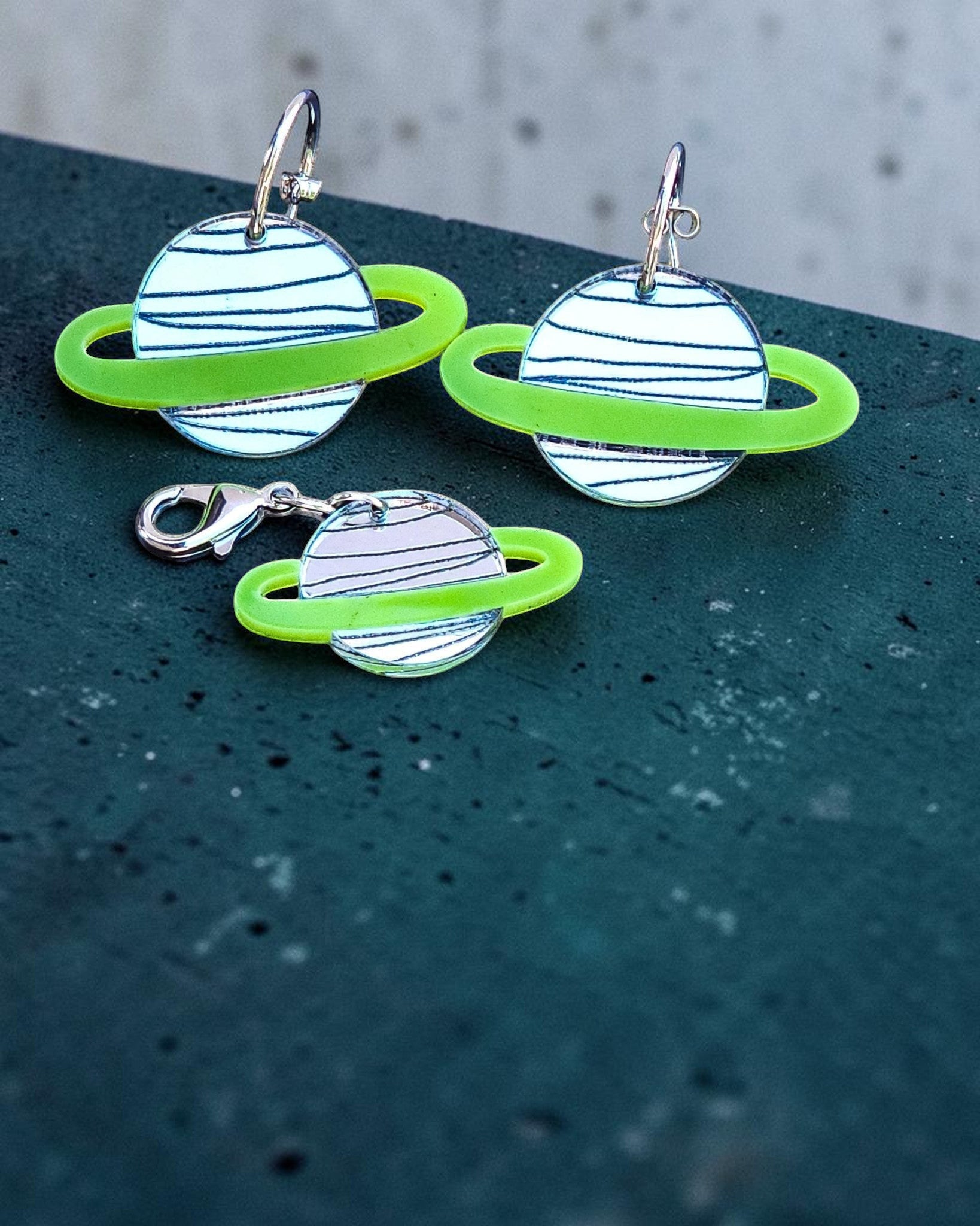 Morti's Fun Club Solar System twinning set featuring green and silver acrylic planet earrings and a matching charm.