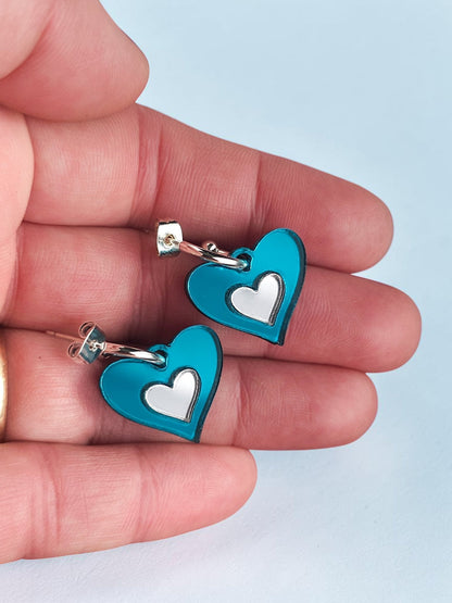 Morti's Fun Club Ice Queen heart earrings featuring shimmering teal acrylic and silver inlay on silver-plated hoops.