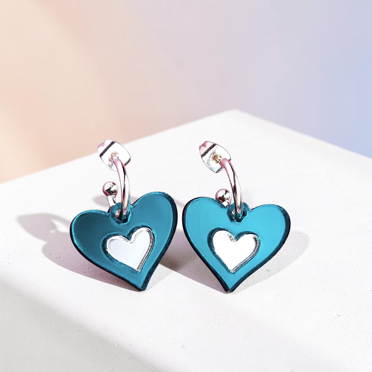 Morti's Fun Club Ice Queen heart earrings in teal and silver mirrored acrylic with hypoallergenic silver hoops.