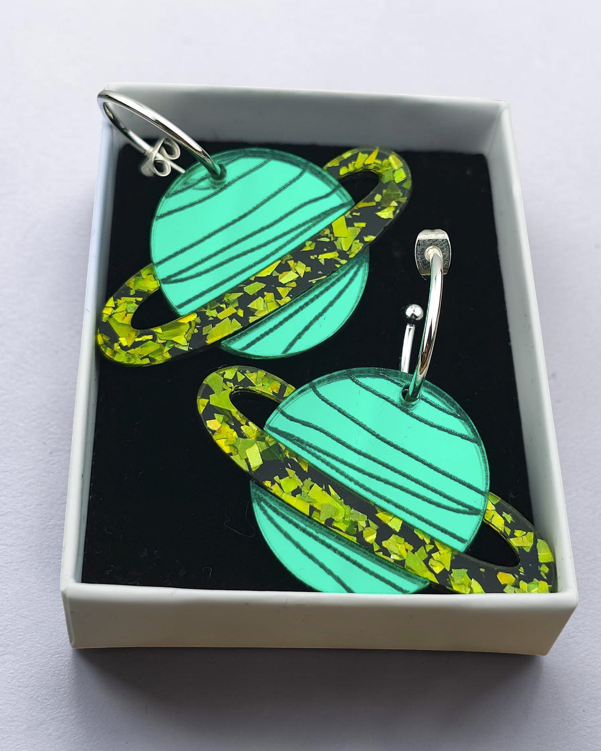 Morti's Fun Club Galaxylicious Green solar system hoop earrings featuring mirrored teal planets and lime glitter rings.